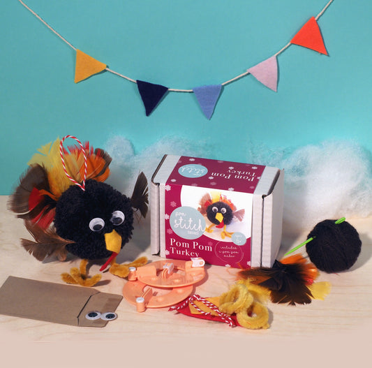 Pom pom turkey craft kit with materials and packaging on a blue background
