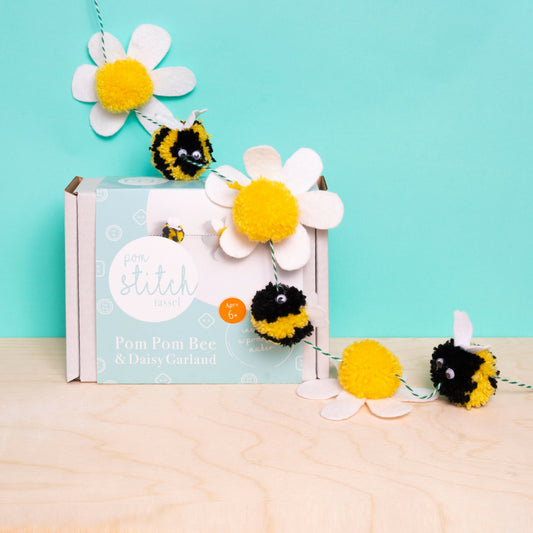 Pom-pom bee and daisy garland set with packaging on a light blue background