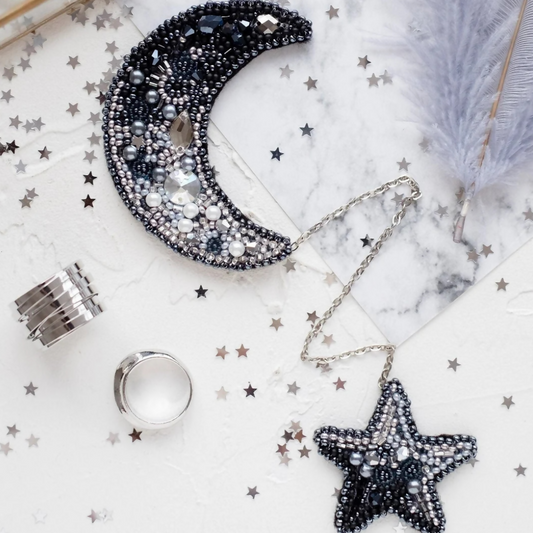 Decorative moon and star jewelry on a marble surface with star confetti