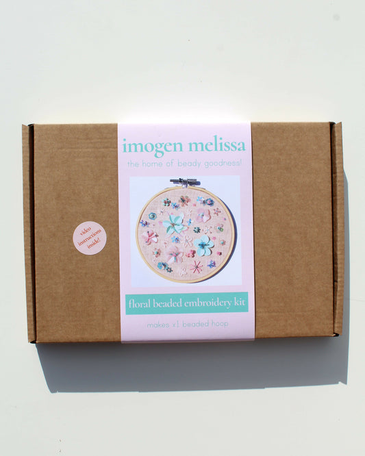Cardboard box with 'imogen melissa' branding and an embroidered hoop design on a white background