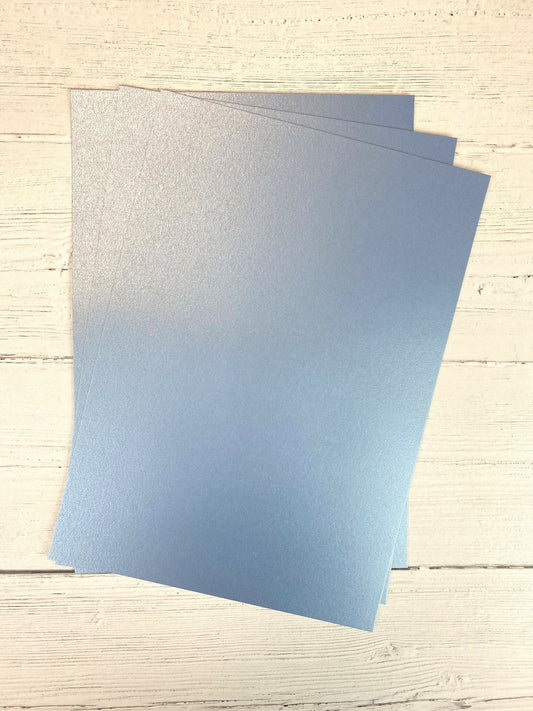 Two blue sheets of Pearl Card on a light wooden surface