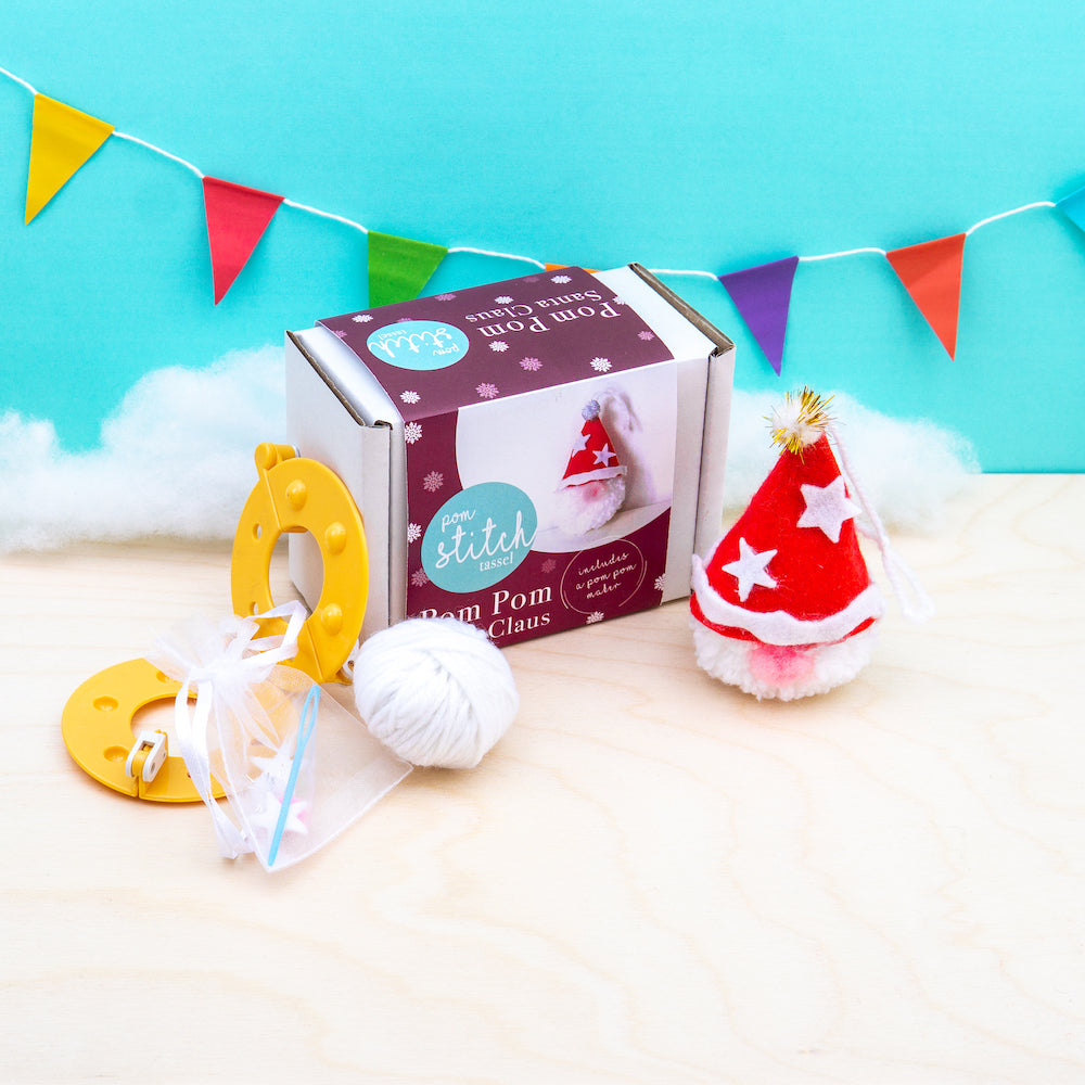 Pom pom craft kit with pom poms and tools on a light blue background