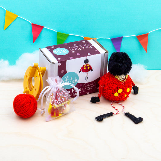 Knitting kit with yarn and tools on a white surface with a colorful banner in the background.