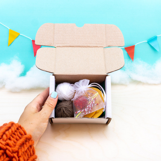 Hand opening a box with craft materials against a colorful background