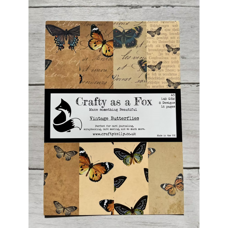 Packaging of 'Crafty as a Fox' vintage butterflies Patterned Paper Pad with butterfly illustrations on a wooden surface.