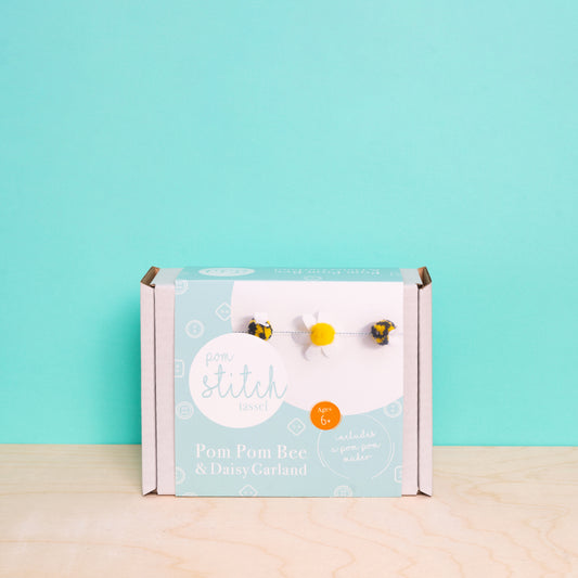 Pom pom bee and daisy garland packaging on a light blue background