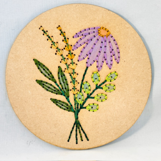 Embroidered design of flowers on a circular wooden board.