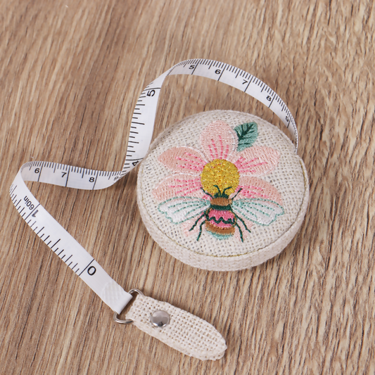 Embroidered Patchwork Bee Tape Measure with tape extended, showing metric and imperial markings