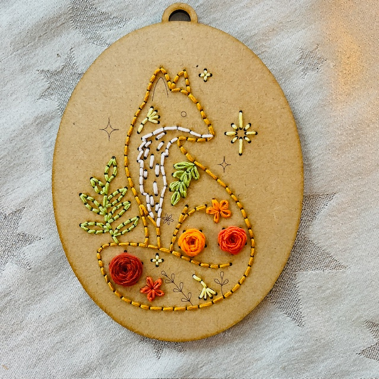 Embroidered design of a fox with flowers on a textured fabric background