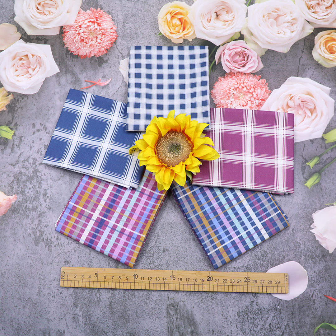 Colorful checkered fabric samples on a gray surface with flowers and a ruler for scale.
