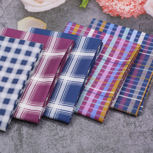 Set of plaid fabric swatches in various colors on a textured surface.