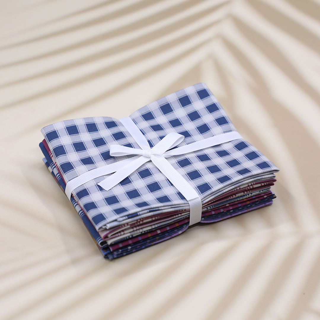 Stack of folded fabric with a white ribbon on a beige surface