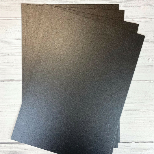 Three sheets of dark gray Pearl Card on a light wooden surface