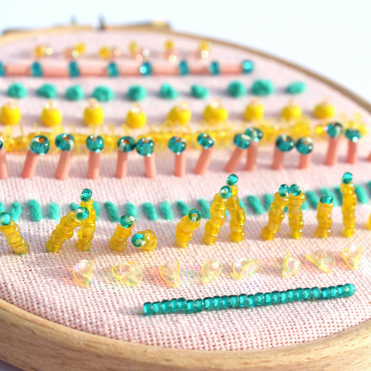 Embroidery hoop with colorful bead patterns on a white background