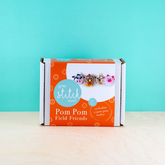 Box of Pom Pom Field Friends with colorful pom-poms on a teal background