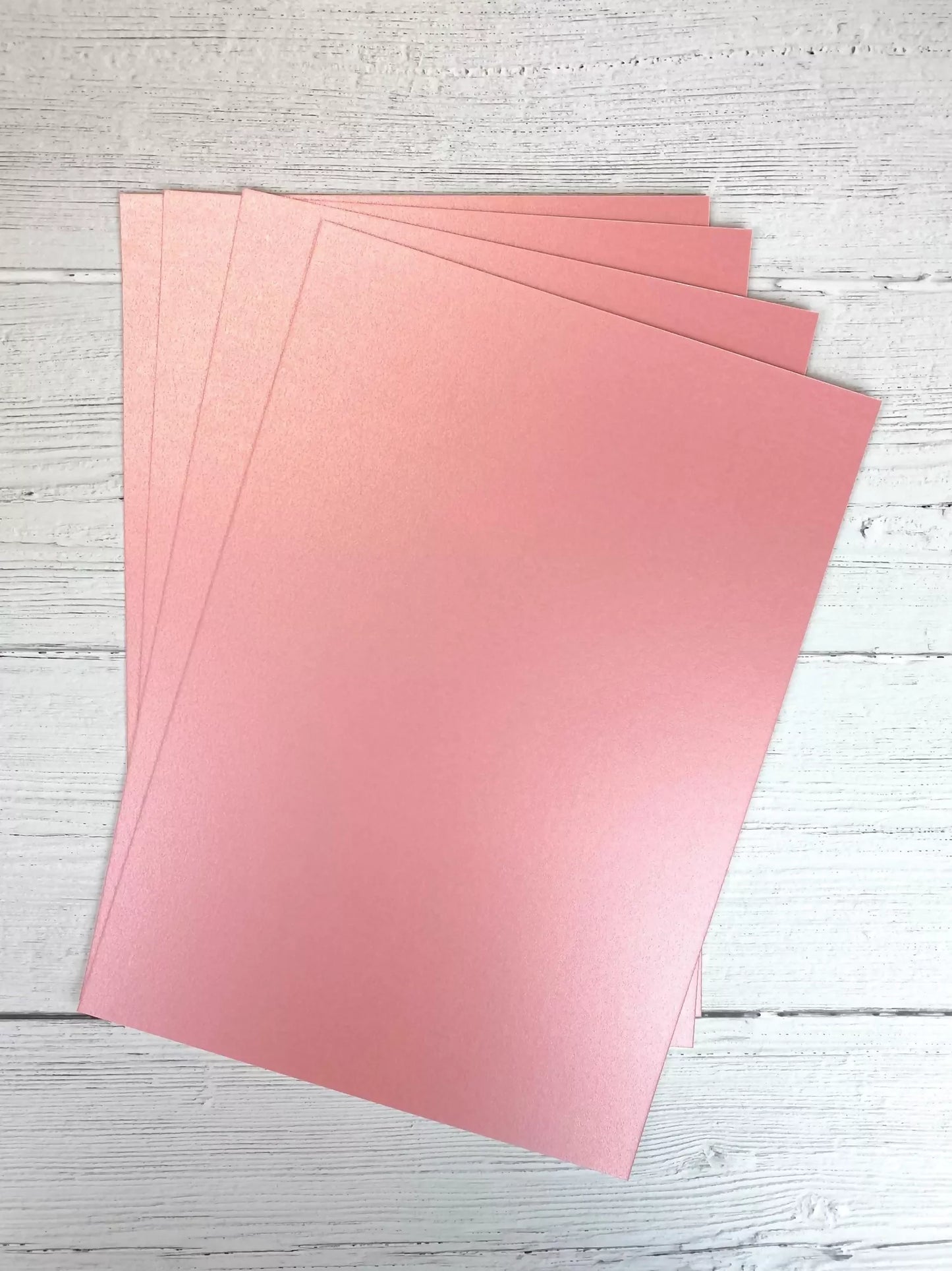 Pink sheets of paper on a light wooden surface