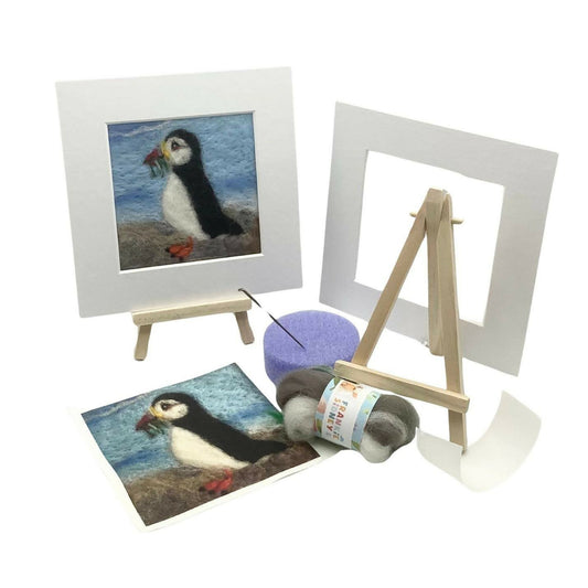 Craft kit with felted puffin, frames, and materials on a white background