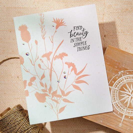 Card with floral design and 'Find beauty in the simple things' text on a wooden surface.