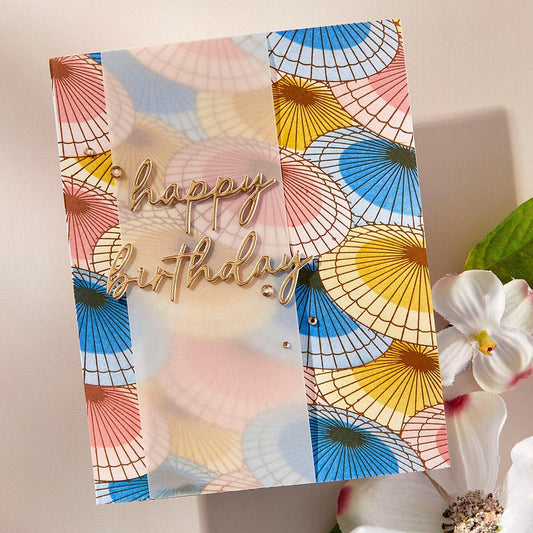Colorful birthday card with geometric patterns and 'happy birthday' text, featuring flowers in the foreground.