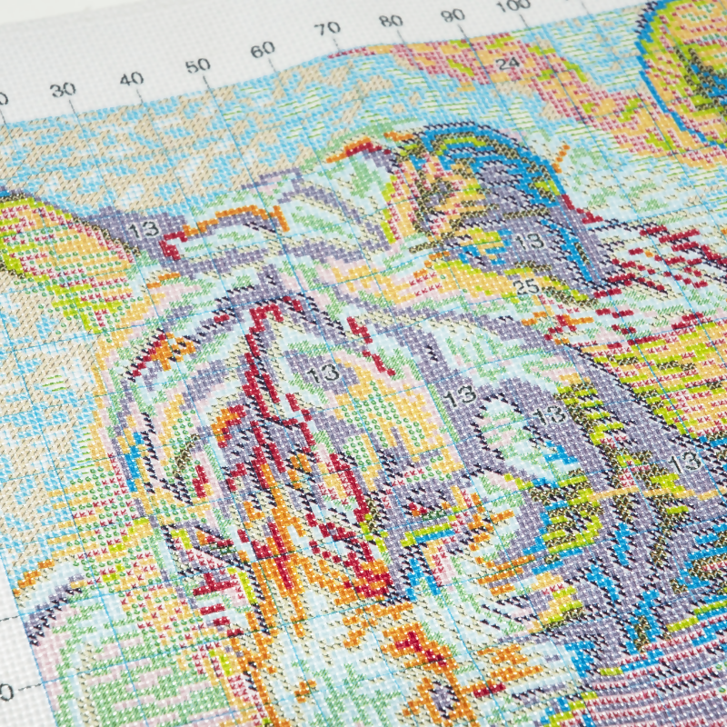 Colourful cross stitch kit of a landscape with a ruler at the top