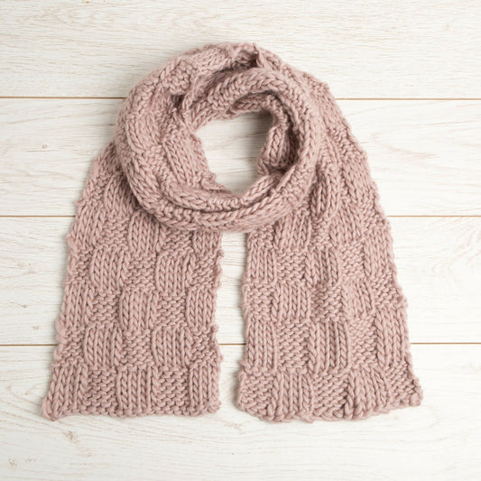Knitted pink scarf on a light wooden surface