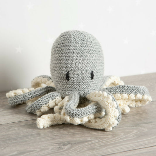 Knitted octopus toy on a wooden surface with a neutral background