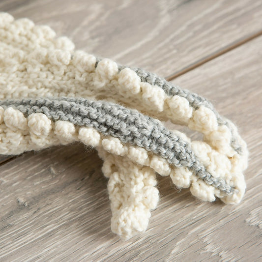 Knitted headband with white and gray pattern on a wooden surface