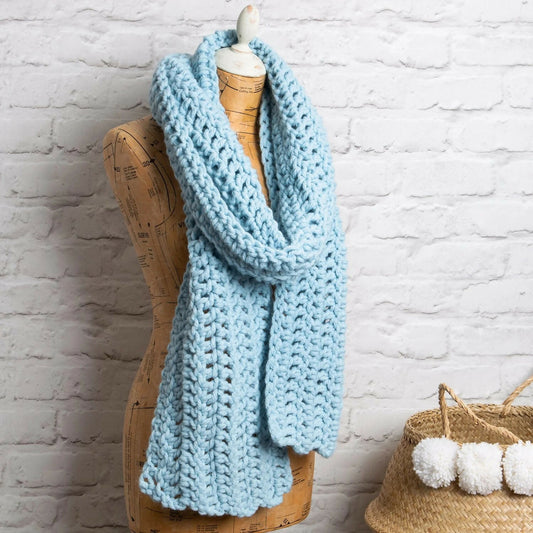 Light blue knitted scarf on a mannequin against a white brick wall.