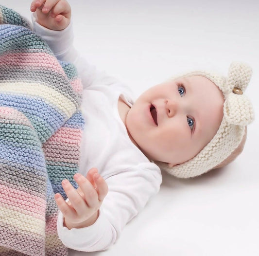 Baby wearing a knitted hat and colorful striped leg warmers on a white background