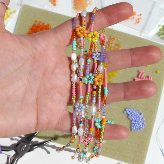 Hand holding colorful beaded bracelets with a crafting background