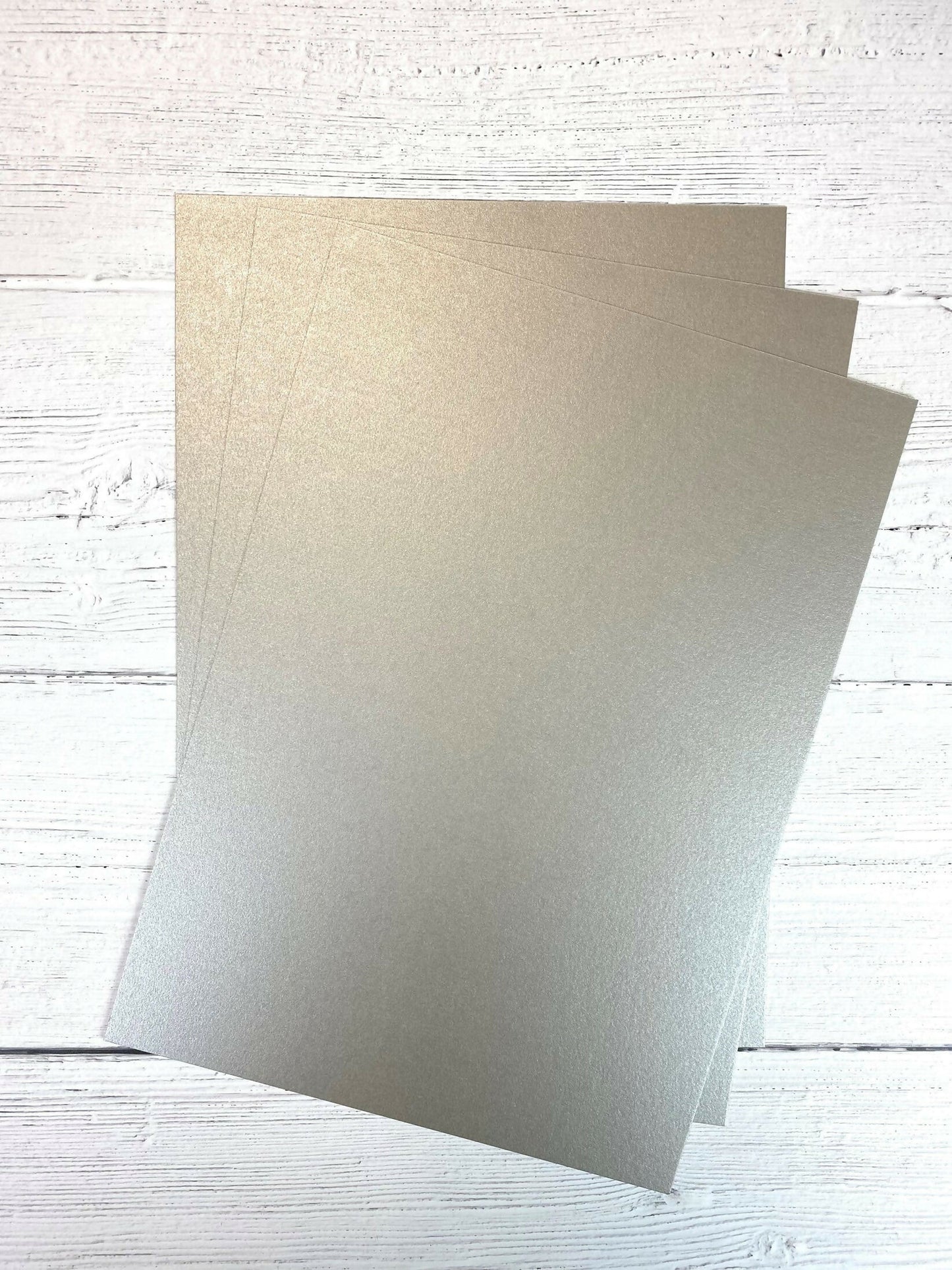 Two sheets of beige paper on a light wooden surface