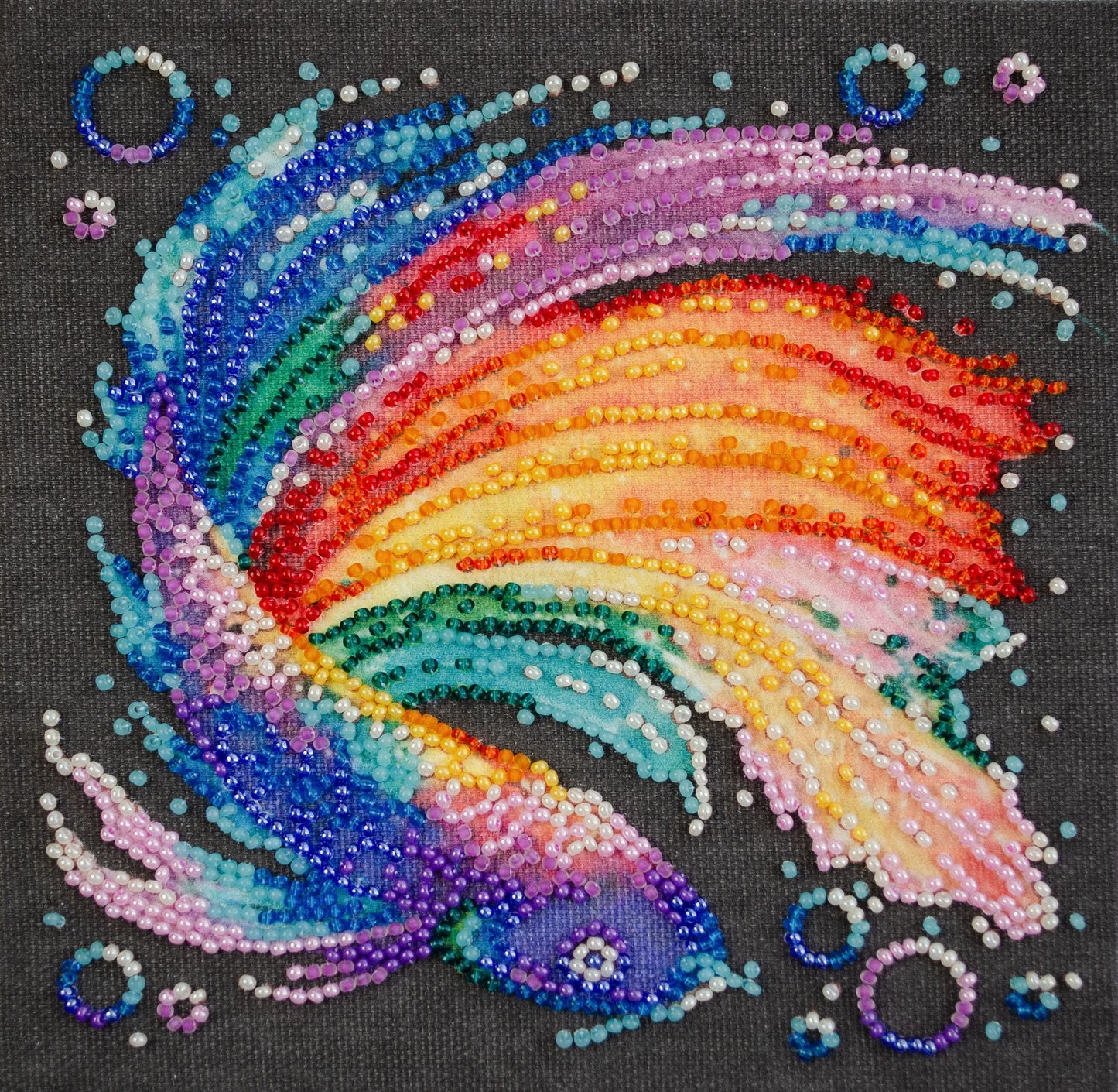 Colorful beaded design of a rainbow on a black background