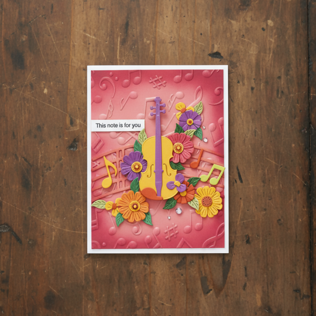 Decorative card with floral and musical design on a wooden surface