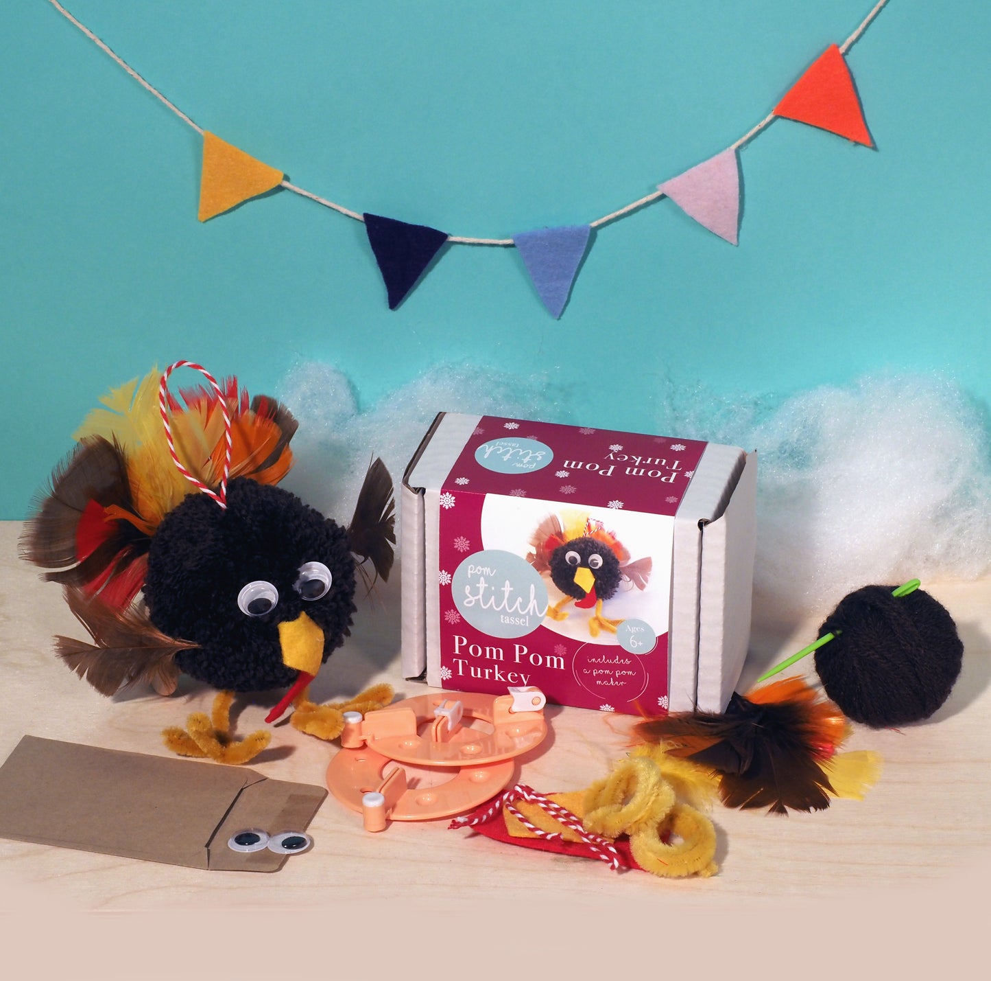 Pom pom turkey craft kit with materials and packaging on a blue background