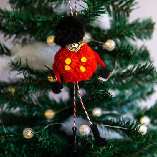 Decorative toy solider ornament on a Christmas tree with lights in the background