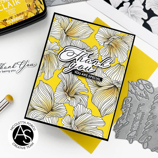 Card with floral design and 'Thank you' message on a white surface with crafting tools.