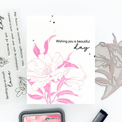 Floral stamp set with pink and white flowers, ink pad, and stamping tool on a white background.