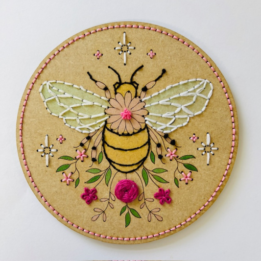 Embroidered bee design on a circular piece of fabric with a white background