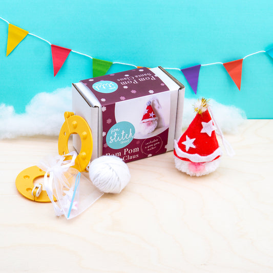 Pom pom craft kit with pom poms and tools on a light blue background