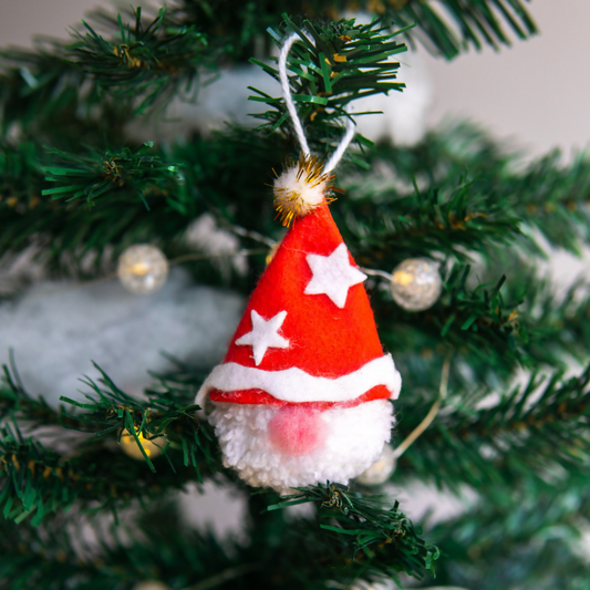 Red Santa hat ornament with white stars on a Christmas tree.
