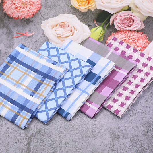 Plaid fabric samples on a gray surface with flowers in the background