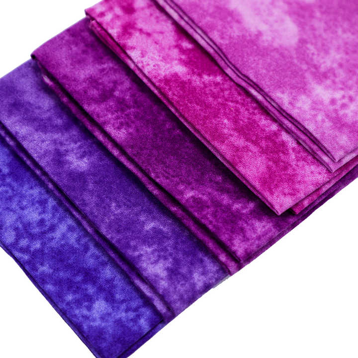 Stack of purple and pink fabric swatches on a white background