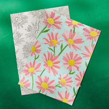Two floral-patterned notebooks on a green background