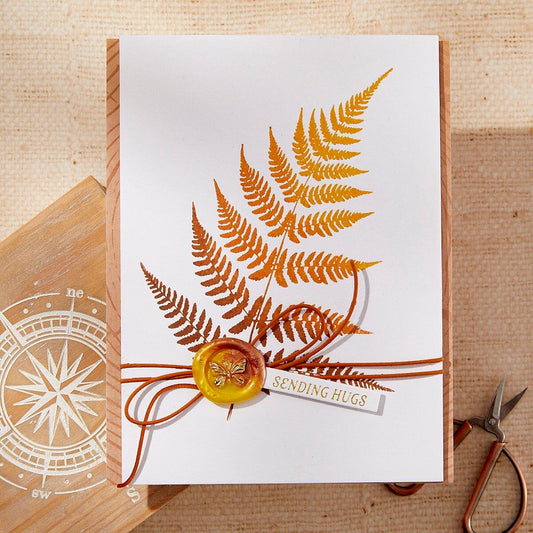 Greeting card with autumn leaf design and 'Sending Hugs' text on a wooden surface.