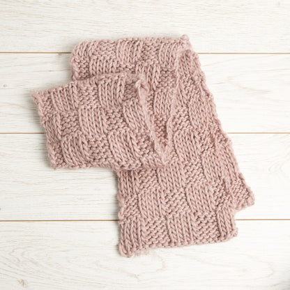 Pair of pink knitted fingerless gloves on a light wooden surface