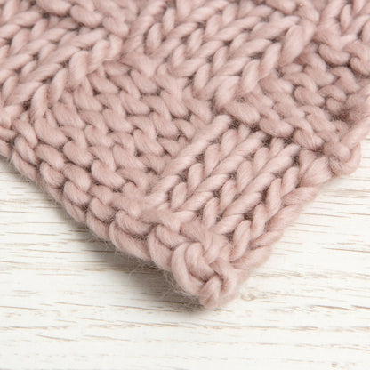 Close-up of a pink knitted fabric on a light wooden surface