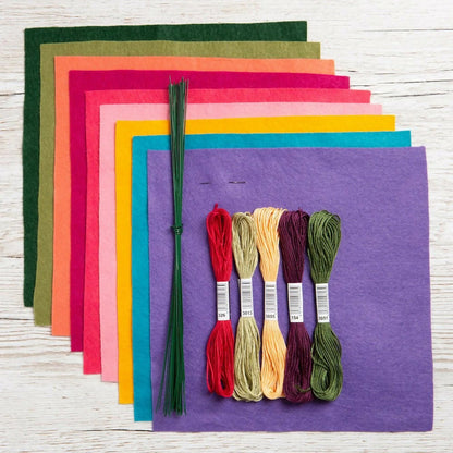 Colorful fabric sheets and embroidery threads on a wooden surface