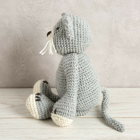 Crocheted gray cat toy on a wooden surface with a neutral background