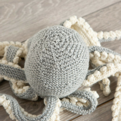 Knitted octopus toy with a textured ball on a wooden surface