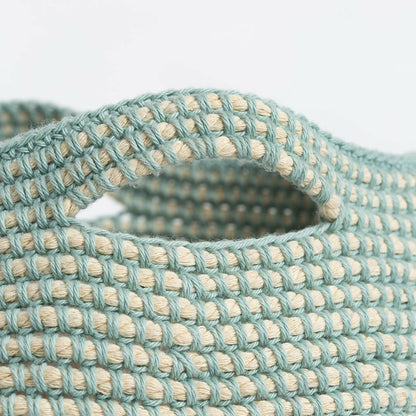 Close-up of a woven belt with a pattern of interlocking loops in teal and beige.